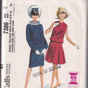以下が含まれることがあります： ヴィンテージMcCall'sの裁縫パターン。2人の女性がドレスを着ています。一人はお揃いの帽子と手袋をつけた濃い青色のドレスを着ています。もう一人は赤いドレスを着ています。パターンにはプリーツスカートとリングスカーフが含まれています。