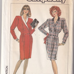 May include: A sewing pattern for two dresses. The dress on the left is red with a white collar and the dress on the right is a plaid pattern with a black collar. The pattern is called Simplicity and the pattern number is 8733.