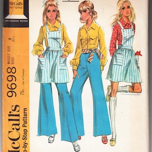 Op de afbeelding: Een vintage naaipatroon voor een dames jumpsuit, broek en blouse. Het patroon is van McCall's en is voor damesmaten 8-31. Het patroon is geïllustreerd met drie vrouwen die de verschillende kledingstukken dragen.