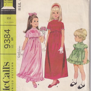 Könnte beinhalten: Vintage McCall's Schnittmuster für Kinderkleider. Das Schnittmuster zeigt Illustrationen von drei verschiedenen Kleiderstilen in Rosa, Rot und Grün. Der Text lautet "Kinderkleid in drei Ausführungen" und enthält das McCall's-Logo.