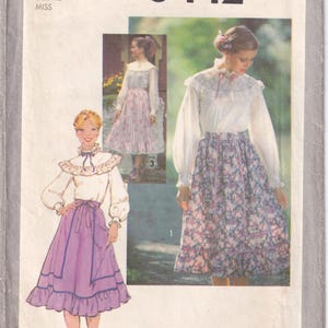 May include: Simplicity pattern 8442 for a Misses' skirt and blouse. The pattern features a white blouse with a ruffled collar and long sleeves, paired with a floral print skirt. The image also shows a purple skirt and blouse.