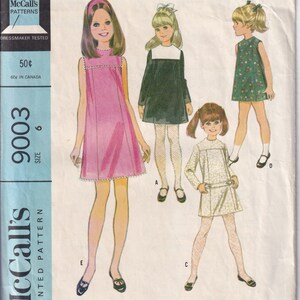 Könnte beinhalten: Vintage McCall's Schnittmuster für Mädchenkleider, Größe 6. Die Illustration zeigt sechs Kleidervarianten in verschiedenen Farben und Stilen. Das Muster enthält den Text "Girls' Dress in Six Versions".