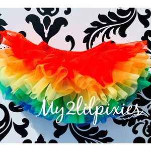 Puede incluir: Falda de tut&uacute; de tul arco&iacute;ris con m&uacute;ltiples capas de tul en rojo, naranja, amarillo, verde, azul y morado. La falda est&aacute; hecha de tul suave y ligero y tiene una cintura el&aacute;stica c&oacute;moda. La falda es perfecta para disfrazarse, fiestas o el uso diario. My2lilpixies est&aacute; impreso en la falda.