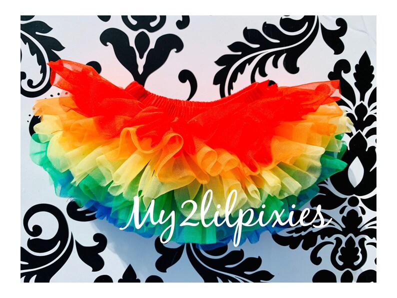 Puede incluir: Falda de tut&uacute; de tul arco&iacute;ris con m&uacute;ltiples capas de tul en rojo, naranja, amarillo, verde, azul y morado. La falda est&aacute; hecha de tul suave y ligero y tiene una cintura el&aacute;stica c&oacute;moda. La falda es perfecta para disfrazarse, fiestas o el uso diario. My2lilpixies est&aacute; impreso en la falda.