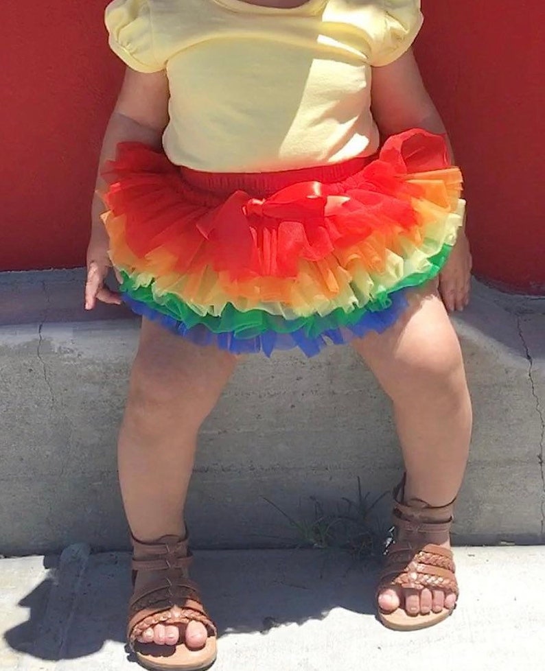 Puede incluir: Un ni&ntilde;o o ni&ntilde;a lleva una camiseta amarilla de manga corta y una falda de tul de arco&iacute;ris. La falda tiene varias capas de tul en rojo, naranja, amarillo, verde, azul y morado.