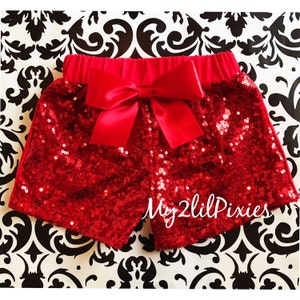 May include: Red sequined shorts with a large red satin bow at the waist. The shorts have a  "My 2 Lil Pixies" logo on the bottom.