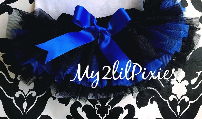 May include: Black tulle tutu with a royal blue satin bow and the text "My 2 Lil Pixies" on the front.