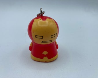 May include: A red and yellow Iron Man character keychain. The keychain is made of plastic and has a silver ring.