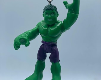 May include: Green Hulk action figure keychain with a purple waistband. The figure is in a dynamic pose with one arm raised.