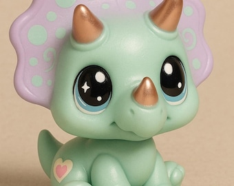 May include: A mint green triceratops figurine with a lavender frill and gold horns. The dinosaur has large, expressive eyes with blue accents and a pink heart detail. A cute, collectible toy.