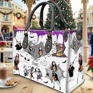 May include: White tote bag featuring illustrations of characters from "The Nightmare Before Christmas." The bag has black handles and a purple glitter trim. The bag is sitting on a wooden table with a cup of hot chocolate and a gingerbread cookie.