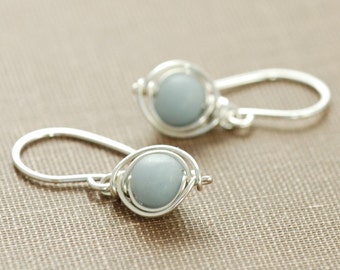 May include: A pair of silver wire wrapped earrings with light blue gemstone beads.