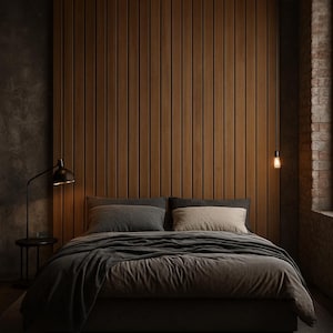 Puede incluir: Un dormitorio moderno con una estética oscura y melancólica. El punto focal es una cama con ropa de cama gris, colocada contra una pared de paneles de madera. Una lámpara negra y una mesita auxiliar pequeña están a la izquierda. Una lámpara colgante y una pared de ladrillo están a la derecha.