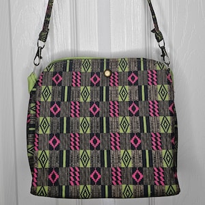Cartera hecha a mano para adulto con estampado marrón, verde y rosa, con correas para el hombro, bolsillo exterior e interior con cremallera y cierre a presión.