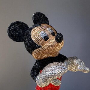 Detailed close-up of the front of the "MICKEY LOVE" Pop Art statue, focusing on the torso, hands, and feet. The image highlights the intricate hand-applied black, gold, and red glass crystals covering the figurine. The silver rhinestone-encrusted gloves and the shimmering red shorts provide a striking contrast to the gold shoes. This exclusive, signed collectible sculpture by artist NOISYX showcases a luxurious, bling aesthetic with impeccable craftsmanship.