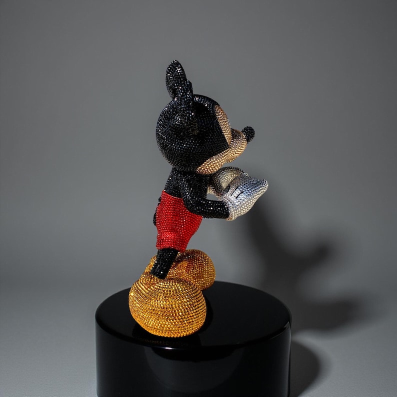 Detailed side profile of the "MICKEY LOVE" Pop Art statue by artist NOISYX. The exclusive collectible sculpture is covered in high-quality hand-applied black, gold, and red glass crystals. The image highlights the figurine's face and ears, and the sparkling texture of the rhinestones. This signed, handmade art object is a premium collectible, perfect for luxury home decor and for collectors of unique pop culture art.