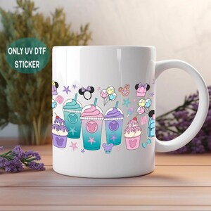 A white ceramic mug with a colorful illustration of various desserts and whimsical characters on it, placed on a wooden surface.