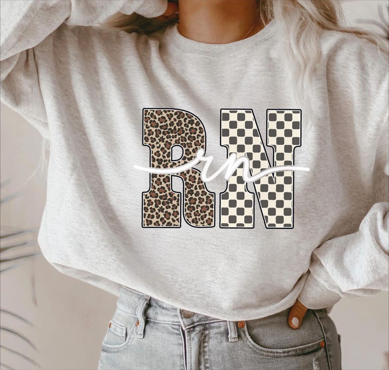 A woman wearing a grey sweatshirt with a leopard print design and the letters "RN" printed on it.