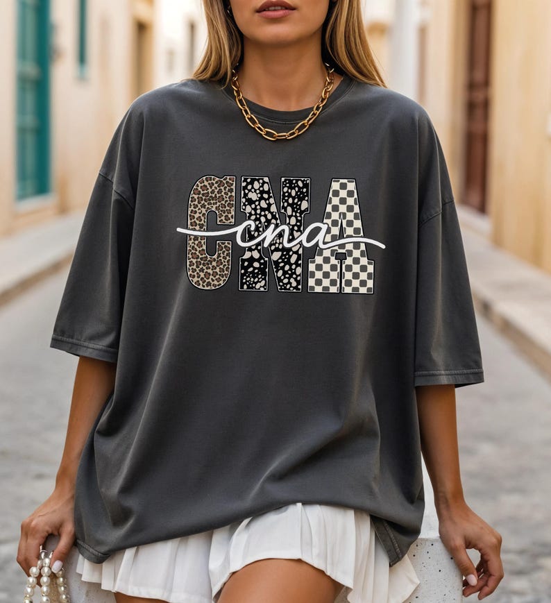 A woman wearing a grey t-shirt with a graphic design and white shorts is walking down a street.