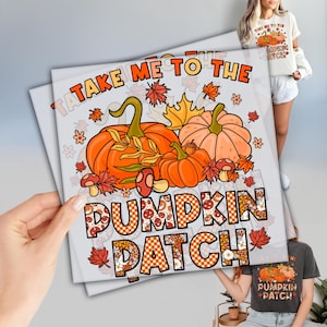 May include: A white t-shirt with a fall-themed graphic that says "TAKE ME TO THE PUMPKIN PATCH". The design features orange pumpkins, fall leaves, and mushrooms. The text "PUMPKIN PATCH" is in a plaid and floral pattern.