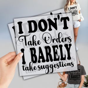 May include: A stack of light gray square prints with the text "I DON'T Take Orders I BARELY take suggestions" in black. The image also shows a person wearing a t-shirt with the same text.