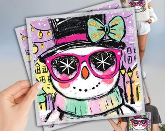 Könnte beinhalten: Quadratischer Kunstdruck mit einem skurrilen Schneemann-Design. Der Schneemann trägt eine rosa Sonnenbrille, einen schwarzen Zylinder und eine mintgrüne Schleife mit goldenen Glitzerakzenten. Der Hintergrund zeigt eine Winterszene mit Straßenlaternen und Gebäuden.