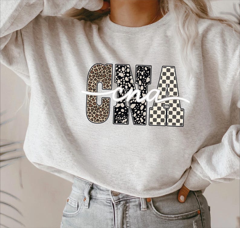 A woman wearing a grey sweatshirt with the letters "CNA" printed on it.