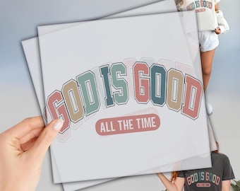 May include: A white graphic tee shirt with the text "God is Good" in a colorful arched font with the words "All the Time" underneath.