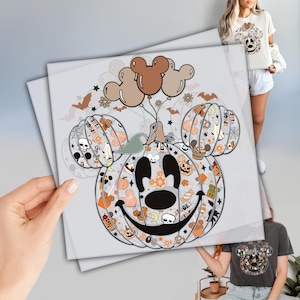 May include: A Halloween-themed graphic featuring a pumpkin with Mickey Mouse ears, filled with Halloween icons. The pumpkin is decorated with bats, stars, and balloons. The design is printed on a light-colored background.