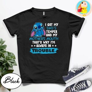Op de afbeelding: Zwart T-shirt met een blauw stripfiguur en de tekst "I GOT MY DAD'S TEMPER AND MY MOTHER'S MOUTH THAT'S WHY I'M ALWAYS IN TROUBLE." Het shirt heeft een ronde hals en korte mouwen.