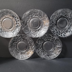 May include: Set of five clear glass saucers with a grapevine design. The saucers are perfect for serving coffee, tea, or dessert.