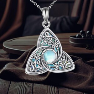 May include: A silver Celtic knot pendant necklace with a blue and green abalone shell inlay. The pendant is in the shape of a triquetra, a symbol of the Trinity.