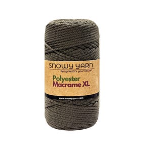Puede incluir: Un carrete de hilo de macramé de poliéster verde oliva. La etiqueta dice "Snowy Yarn" con el texto "Polyester Macrame XL" y la dirección del sitio web. El hilo está bien enrollado, listo para proyectos de manualidades.