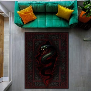 May include: A rectangular rug with a detailed design featuring a black snake emerging from a red and black background. The rug has a decorative border and is placed on a light gray floor. A green sofa with yellow and orange pillows is above the rug.