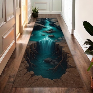 May include: A rectangular rug depicting a waterfall scene. It features a turquoise river flowing through a canyon with rocky cliffs and a cascading waterfall. The rug is placed on a wooden floor.