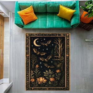 May include: A rectangular rug with a dark background featuring a crescent moon, bats, trees, and flowers. The rug has a decorative border with floral elements. The color palette includes black, gold, and shades of brown and orange.
