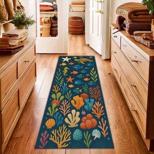 May include: A rectangular, dark blue rug with a vibrant underwater scene. The design features colorful coral, fish, seahorses, and a sea turtle. The rug is placed on a wooden floor, adding a decorative touch to the space.