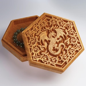 May include: Hexagonal wooden box with a carved dragon design on the lid. The box is open, revealing a green beaded bracelet inside. The box is made of light brown wood and has intricate carvings.