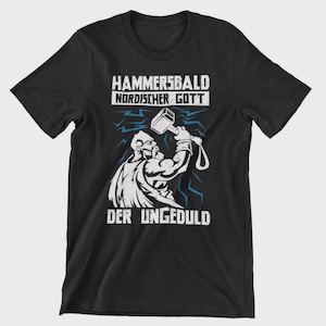 Könnte beinhalten: Schwarzes T-Shirt mit weißer Grafik einer Figur mit Hammer, Text "HAMMERSBALD NORDISCHER GOTT" und "DER UNGEDULD" in Weiß. Blaue Blitze ergänzen das Design.