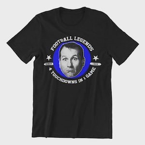 Könnte beinhalten: Schwarzes T-Shirt mit einem Porträt eines Mannes in einem blauen Kreis, mit dem Text "FOOTBALL LEGENDS" und "4 TOUCHDOWNS IN 1 GAME". Das Shirt enthält auch den Namen "BUNDY" und das Jahr "1966".
