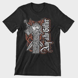 Könnte beinhalten: Schwarzes T-Shirt mit einer detaillierten Illustration eines bärtigen Kriegers mit Schwert und Helm. Das Design enthält den Text "Auf alte Götter" in einer vertikalen, stilisierten Schriftart mit roten und weißen Akzenten. Das Thema ist nordische Mythologie.