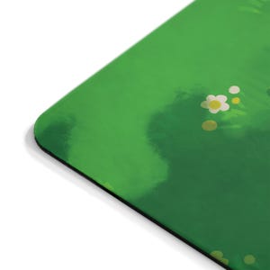 Puede incluir: Un tapete para rat&oacute;n verde y blanco con un sutil efecto acuarela. El tapete para rat&oacute;n presenta un dise&ntilde;o de flores blancas con centros amarillos sobre un fondo verde.