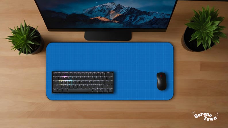 May include: A top-down view of a computer setup featuring a blue mousepad, a black keyboard, and a black mouse. A computer monitor displays a mountain scene. Two potted plants flank the setup on a wooden desk.