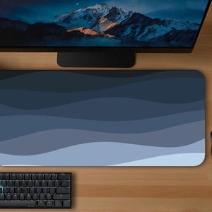 May include: A blue and white patterned mousepad with a black keyboard and mouse. The mousepad has a wave design in shades of blue. A computer monitor and two potted plants are also visible.