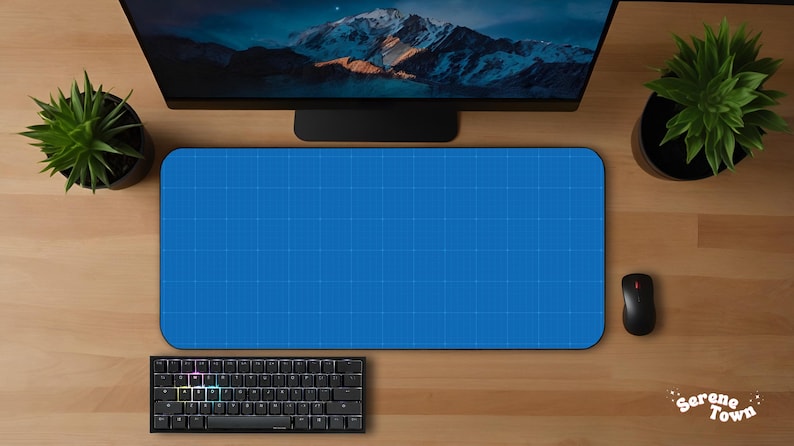 May include: Overhead shot of a computer setup on a wooden desk. A blue mousepad with a grid pattern is centered, with a black keyboard, mouse, and monitor. Two potted plants flank the monitor. The keyboard has colorful backlit keys.