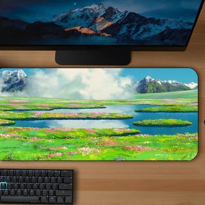 May include: A colorful mousepad with a scenic landscape featuring a grassy field, a lake, and mountains in the background. The sky is blue with white clouds.