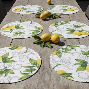 Peut inclure: Six ronds de table avec un motif de citron et de feuilles sont disposés sur une table en bois. Les ronds de table présentent un fond blanc avec des citrons jaunes, des feuilles vertes et des contours gris esquissés. Des citrons frais et des feuilles sont également placés sur la table.