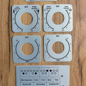 May include: A set of light gray square stove control knob overlays for Frigidaire #PLES389DCB. The overlays feature black printed text and circular markings for Front, Bridge, Small, and Large elements, plus a sheet with indicator icons and labels.