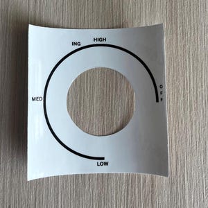 May include: A white ceramic mug with a black handle and the text "But First, Coffee" in a bold, black font. The mug is set against a blurred background, suggesting a cozy setting.