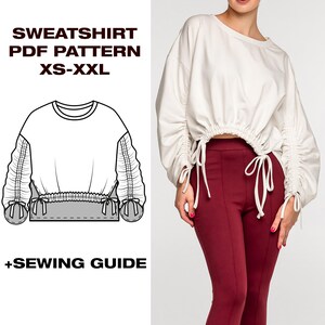 May include: A white sweatshirt with gathered sleeves and a drawstring waist is paired with burgundy pants. The image also includes a line drawing of the sweatshirt pattern, with the text "SWEATSHIRT PDF PATTERN XS-XXL" and "+SEWING GUIDE".